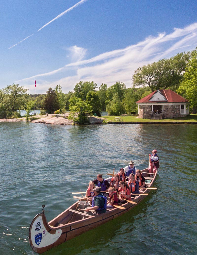 Dix personnes dans un canot montréalais, sur l'eau et près du rivage