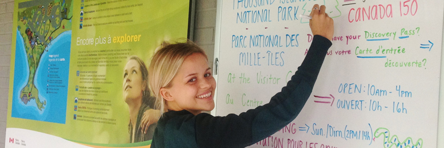 A student staff member writing on an info board. 