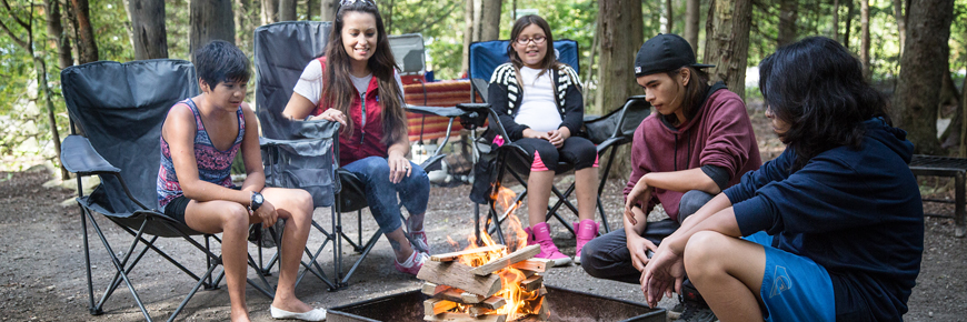 A family sits around a campfire. 