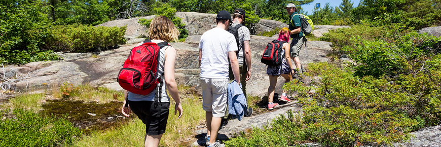 Le personnel du parc dirige un groupe en randonnée sur les rochers.