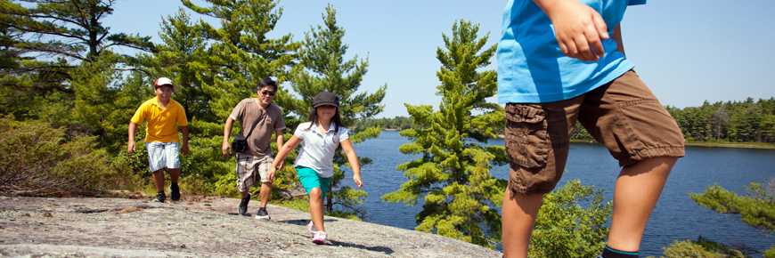A group of visitors hikes along rocky shoreline. 