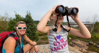 A child and mother look through binoculars. 