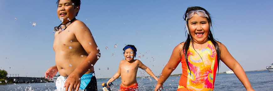 Children splash in the water on a sandy shoreline. 