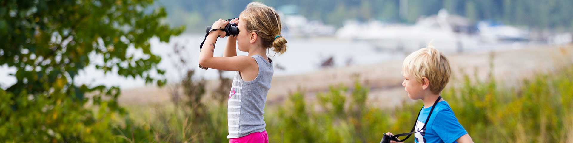 Two kids look through binoculars.
