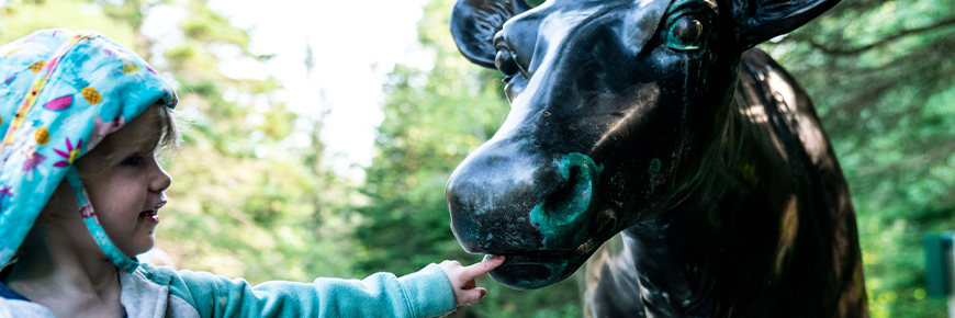 A young visitor interacts with a caribou statue.