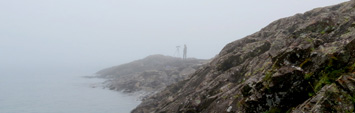  Une personne debout sur une rive rocheuse dans le brouillard.