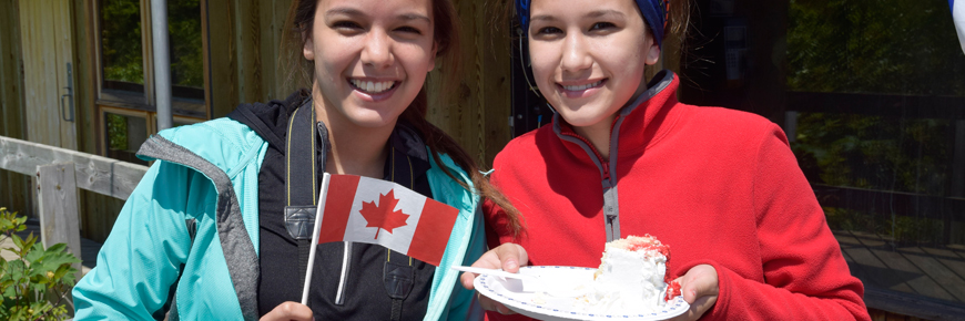 Two girls with cake and a Canadian Flag