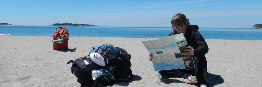 A person with a map sitting on a beach.