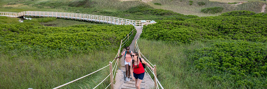 Two young females laughing as they approach the top of the Greenwich Dunes Trail. 