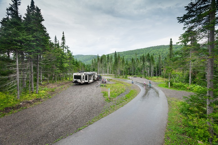 A recreational vehicle is parked at a campsite. The road around it is paved.