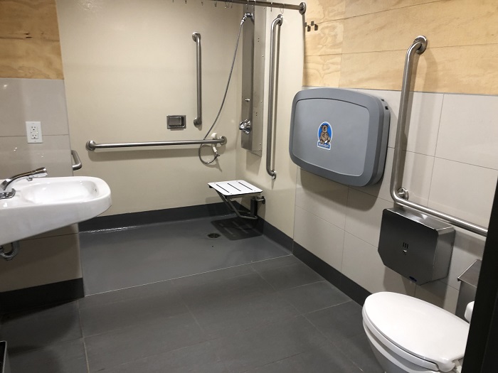 Une toilette et une douche accessibles aux personnes à mobilité réduite dans la même pièce de l'un des bâtiments de service du camping Des-Rosiers.