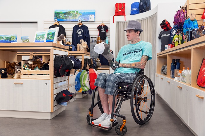Un homme en fauteuil roulant magasine dans la boutique du centre d'accueil et de découverte.