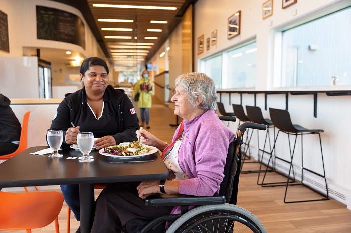 Deux femmes, dont une en fauteuil roulant, partagent un repas au Bistro au Havre de Forillon.
