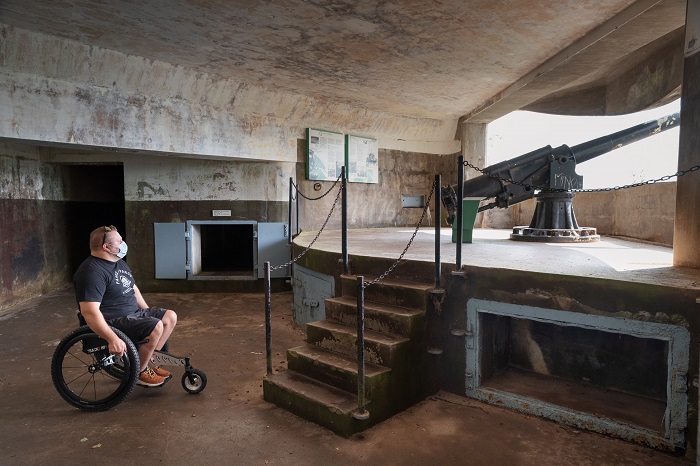 A man in a wheelchair admires an authentic cannon inside the Fort Peninsula underground fortifications. 