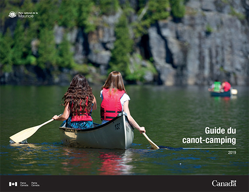 Couverture du guide de canot-camping 2019 en version française - deux jeunes canoteuses de dos pagayant sur un lac calme