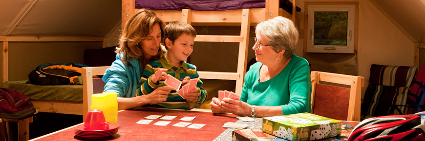 Trois générations jouant aux cartes sur la table d'une oTENTik
