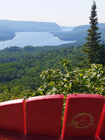 Le dessus d'un dossier de chaise rouge avec en arrière-plan le lac Rosoy