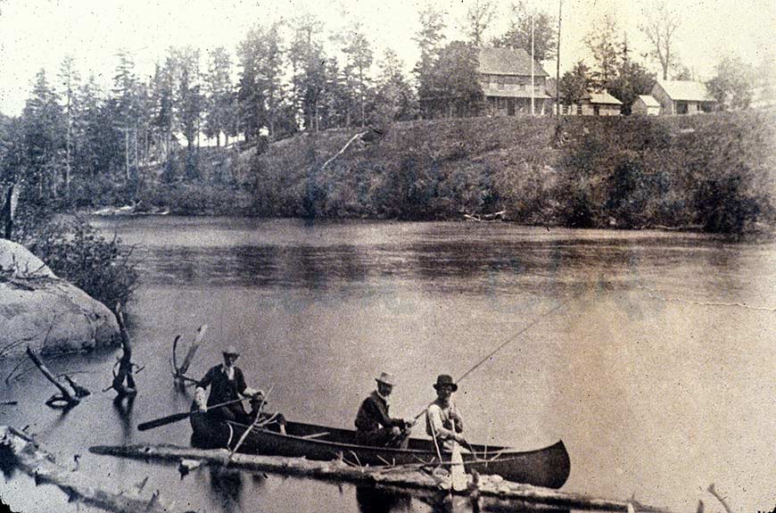 Trois hommes en canot, celui du centre pêche.