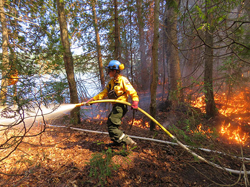 Une employée de Parcs Canada contrôle la propagation d'un brûlage dirrigé