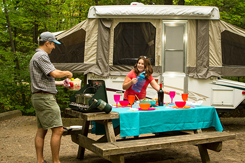 Father and daughter cooking in front of a trailer-tent