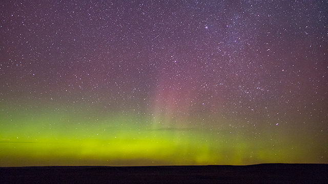 La Voie lactée et des aurores boréales dans la réserve de ciel étoilé éblouissent le ciel la nuit, au parc national des Prairies. 