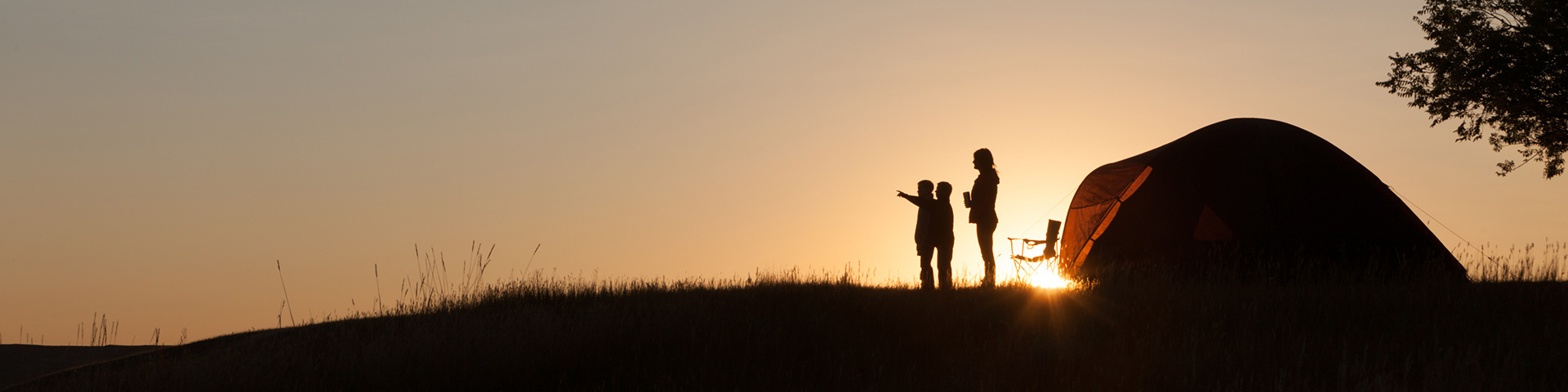 Une petite famille en camping, observe le coucher de soleil.