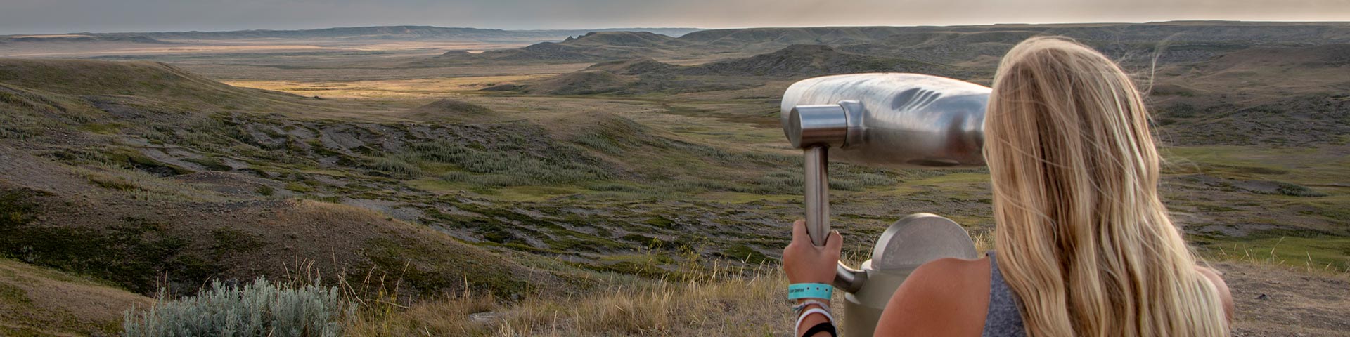 A woman checking out the landscape through a viewing scope in the West Block of Grasslands National Park.