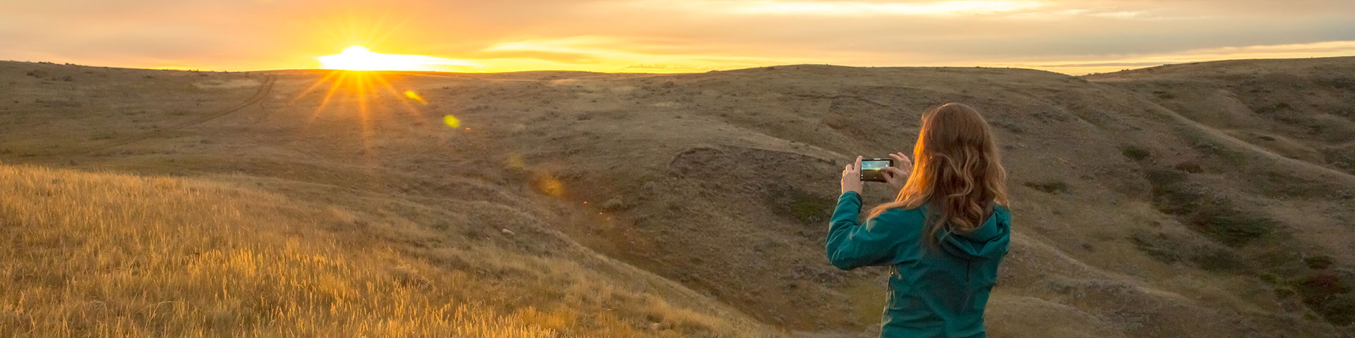 Une femme photographie le lever du soleil en septembre dans le parc national des Prairies.