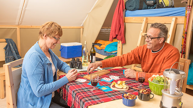 A couple enjoys card games and snacks inside the comfort of their Parks Canada oTENTik, in Grasslands National Park.