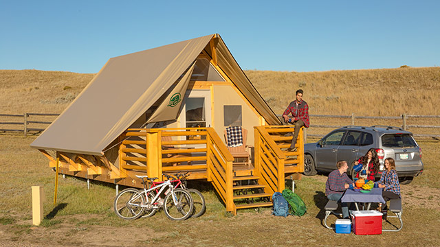 A group of young adults eat breakfast outside their Parks Canada oTENTik at Frenchman Valley Campground, in Grasslands National Park.