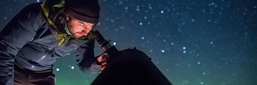 Un visiteur observe le ciel étoilé à l'aide d'un télescope astronomique