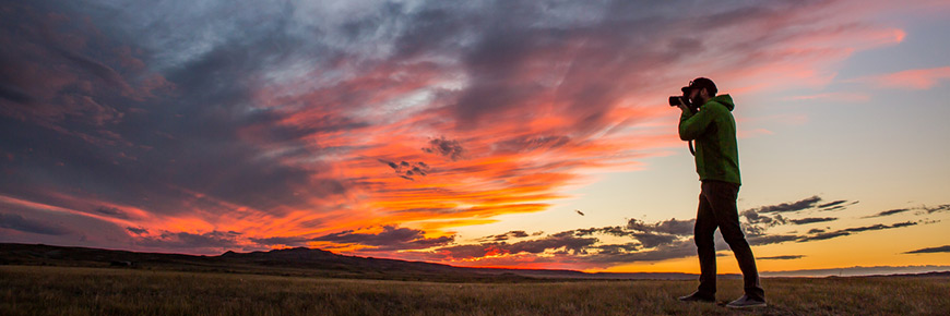 Un photographe de Parcs Canada se découpe sur le coucher du soleil en septembre, dans le parc national des Prairies. 