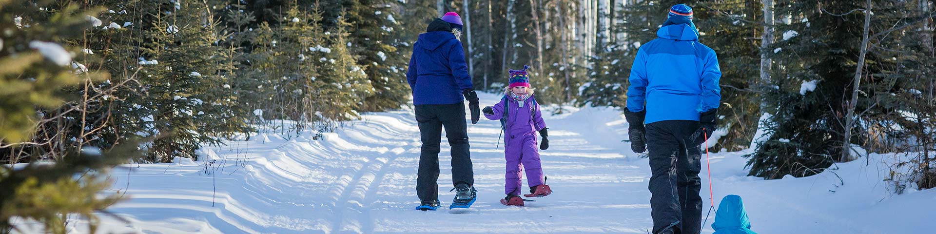Young family snowshoeing through the woods