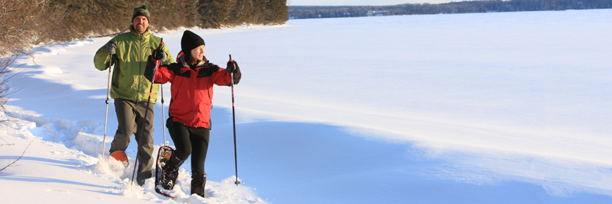 A happy couple look out over the lakes as they snowshoe along the shoreline. 