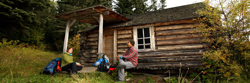 A young couple sits on the porch of Grey Owl’s cabin. 
