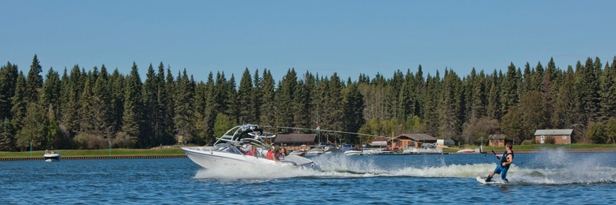Un bateau à moteur tire un adepte de planche nautique sur un lac.