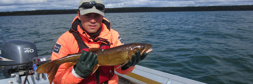A park ecologist holds a Lake Trout for a picture before releasing it back into Kingsmere Lake. 