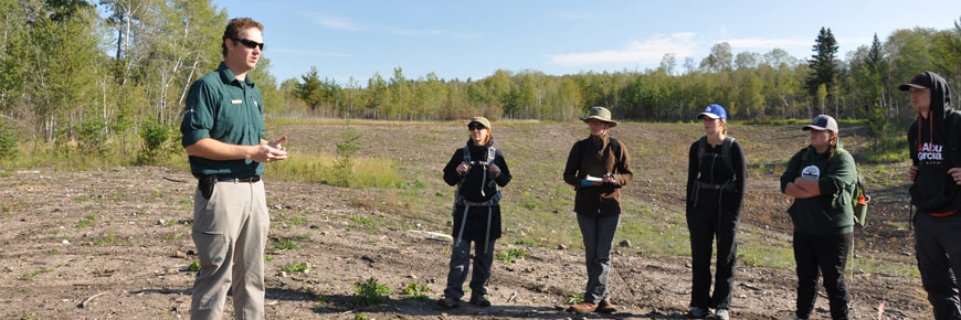A park ecologist chats with a group of students at a borrow pit restoration site. 