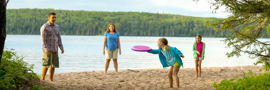 Une famille de quatre personnes joue au Frisbee sur la plage.