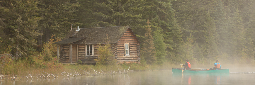 A couple paddle a canoe through the fog to toward Grey Owl’s cabin. 