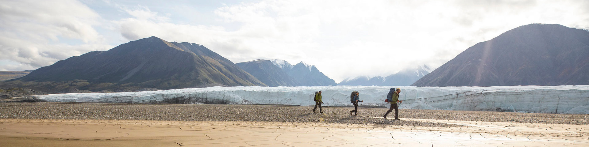 Hikers walk in front of the Donjek Glacier