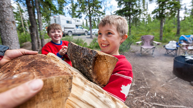 A child smiles and carries firewood