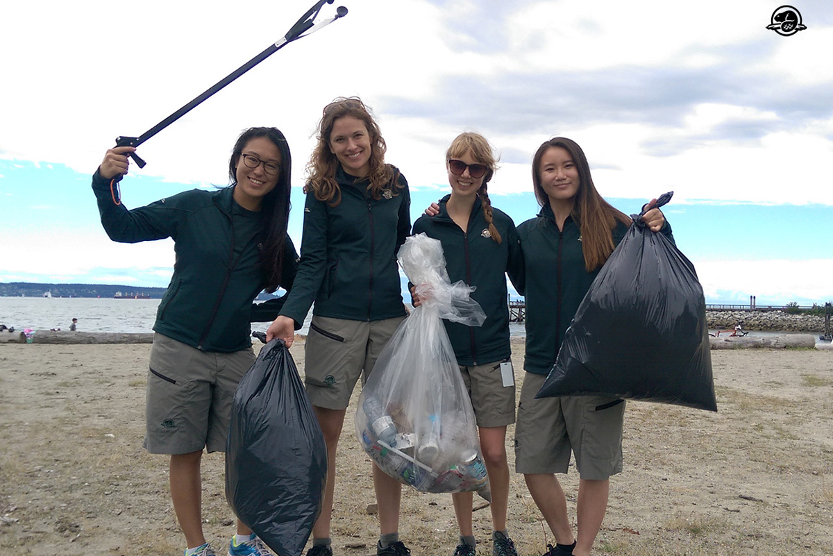 Des membres de l’équipe de Parcs Canada posent avec des pinces à ordures et des sacs-poubelle pleins après avoir nettoyé le rivage.