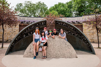 A group of young people pose for a photo at a monument at the Forks.