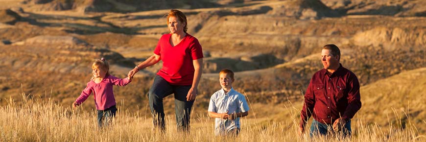 Une famille de quatre personnes observe le coucher du soleil dans les prairies.