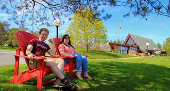 Deux visiteurs assis dans les chaises rouges de Parcs Canada en haut d’une colline