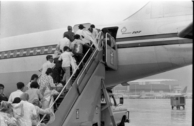 Des réfugiés montent à bord du premier vol du CF707 Hong Kong-Canada, 1979. Photographie attribuée au MCpl Bryantowich. (© Canada.Department of National Defence / Library and Archives Canada | Canada. Ministère de la Défense nationale / Bibliothèque et Archives Canada / e999901766-u)