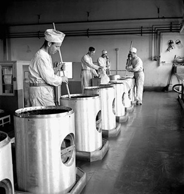 Des ouvriers remuent des produits chimiques utilisés dans la fabrication des cônes de charge aux usines Cherrier et Bouchard de la société Defense Industries Limited. Juillet 1944 © Harry Rowed / Office national du film du Canada. Photothèque / Bibliothèque et Archives Canada |National Film Board of Canada. Photothèque / Library and Archives Canada